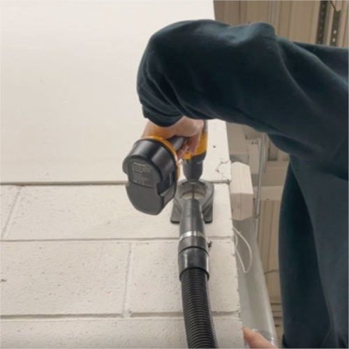 Close-up of Alpha Ecoguard CD connected to a vacuum hose during wall drilling