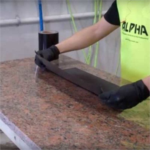 Worker applying Alpha Surface Protection Tape across a granite slab