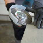 DiStar Edge Dry 4.5″ diamond blade mounted on an angle grinder beside a tile edge