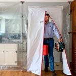 Person entering through ZipDoor Magnetic Door Kit installed on a plastic dust barrier